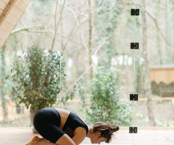 Person stretching on a yoga mat with serene background.